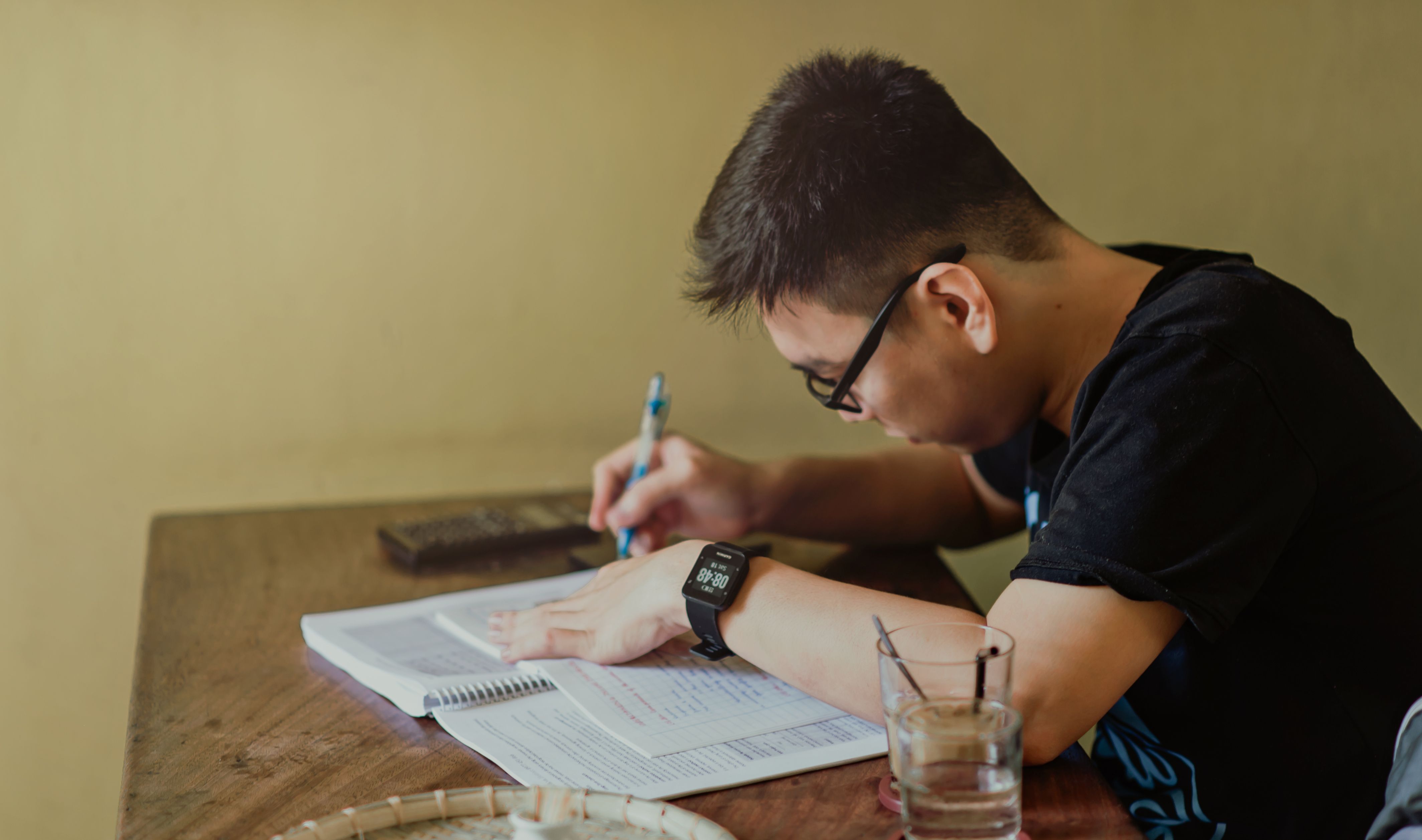 A high-school scholar studying independently at a desk in warm evening light